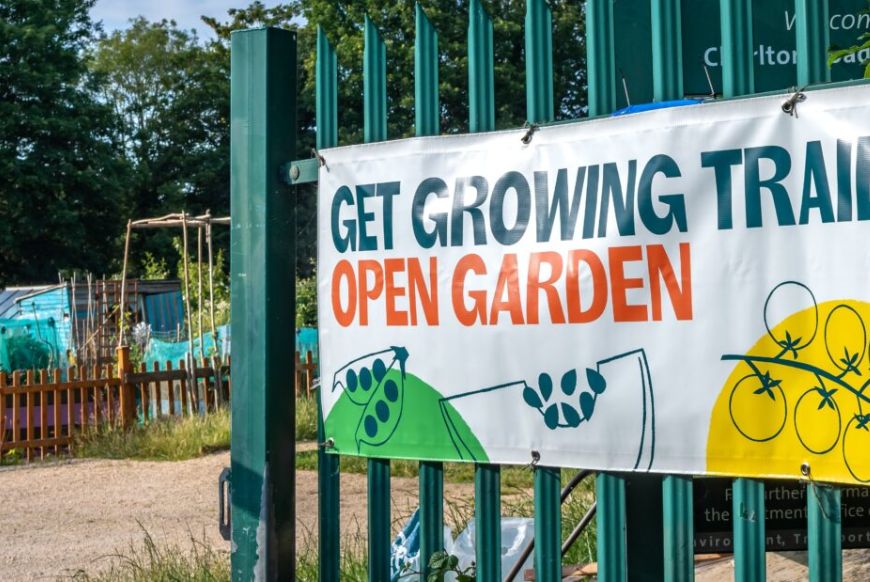 a fence with a sign reading 'get growing trail, open garden' on it